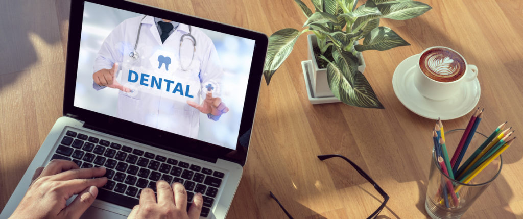 Dental website on a laptop that is on a desk with coffee, glasses and a plant